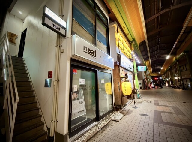 店の入口。商店街の建物の左側に2階へ上がる階段がある